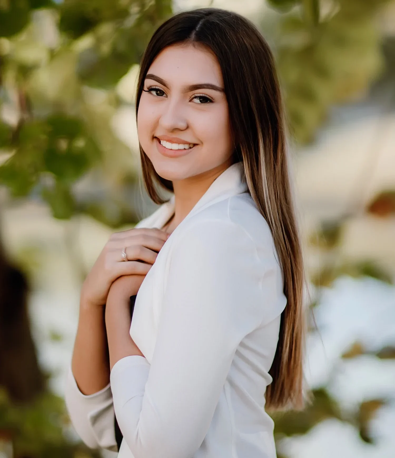 Smiling teen girl wearing white with her hands crossed over her heart | Frisco's Premier Orthodontics